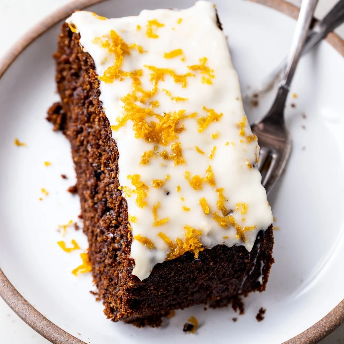 Moist Gingerbread Loaf with Orange Icing cooling on a wire rack, topped with a glossy citrus glaze for a festive treat.