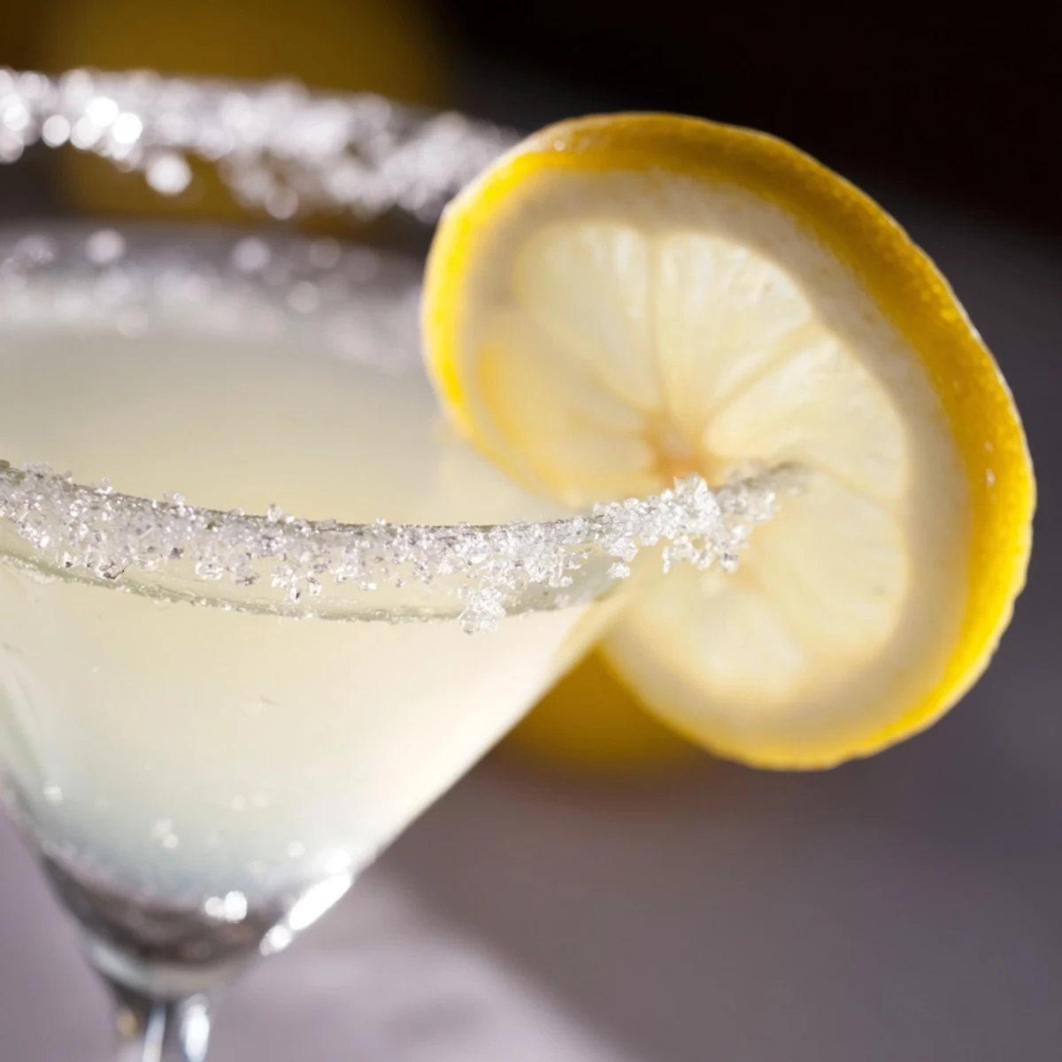 Close-up of Lemon Drop Cocktail preparation, showing sugared rim and fresh lemon juice being poured into a cocktail shaker.