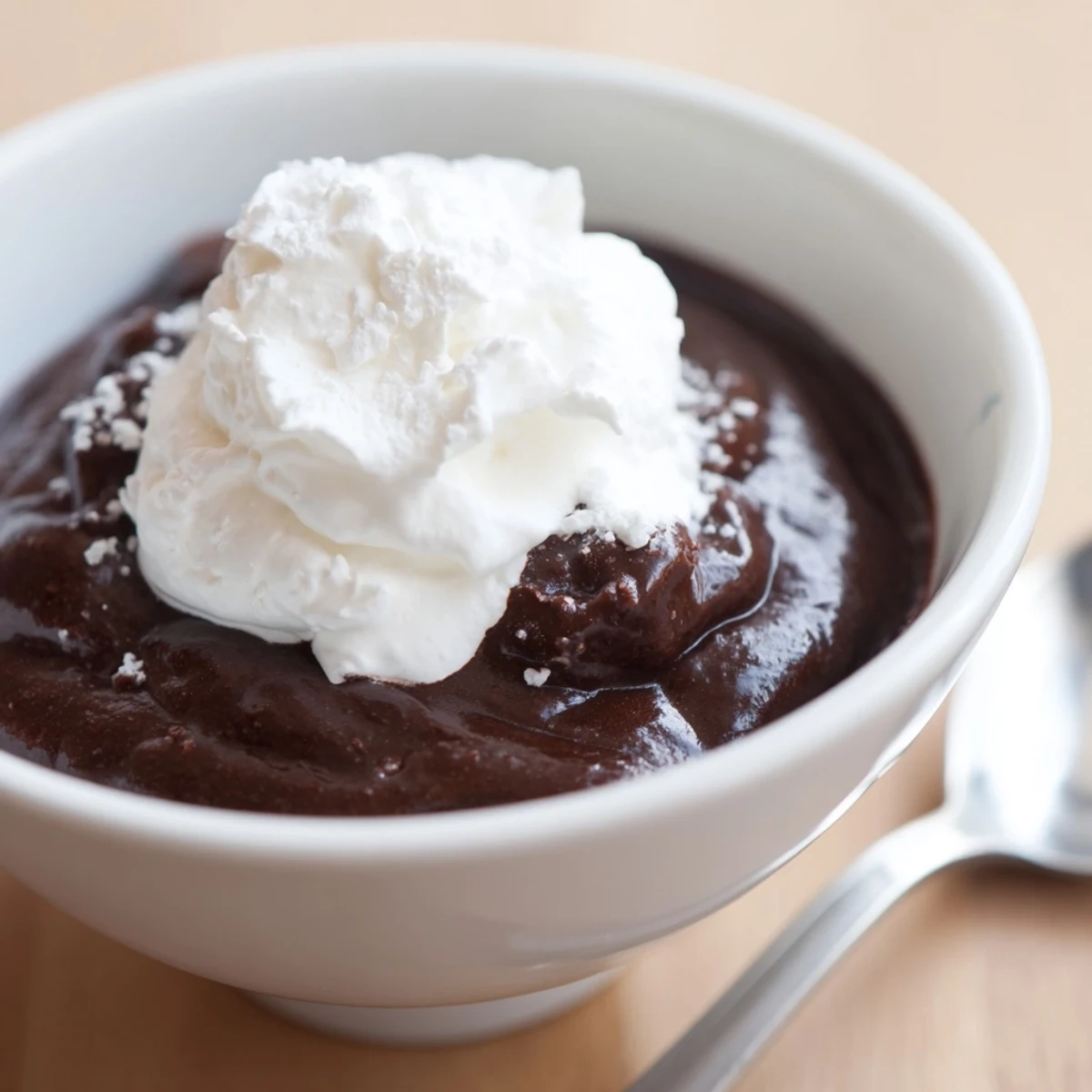 A creamy chocolate pudding topped with a fluffy dollop of fresh whipped cream in a glass.