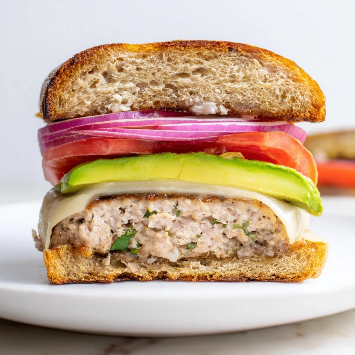 Turkey Burger with Avocado and Swiss Cheese served hot on a plate with tomatoes and crisp lettuce.