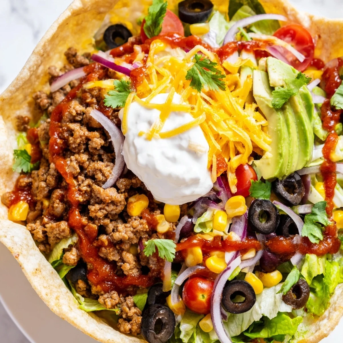 Hearty Tex-Mex Beef Taco Salad with sour cream and salsa, served with lime wedges.