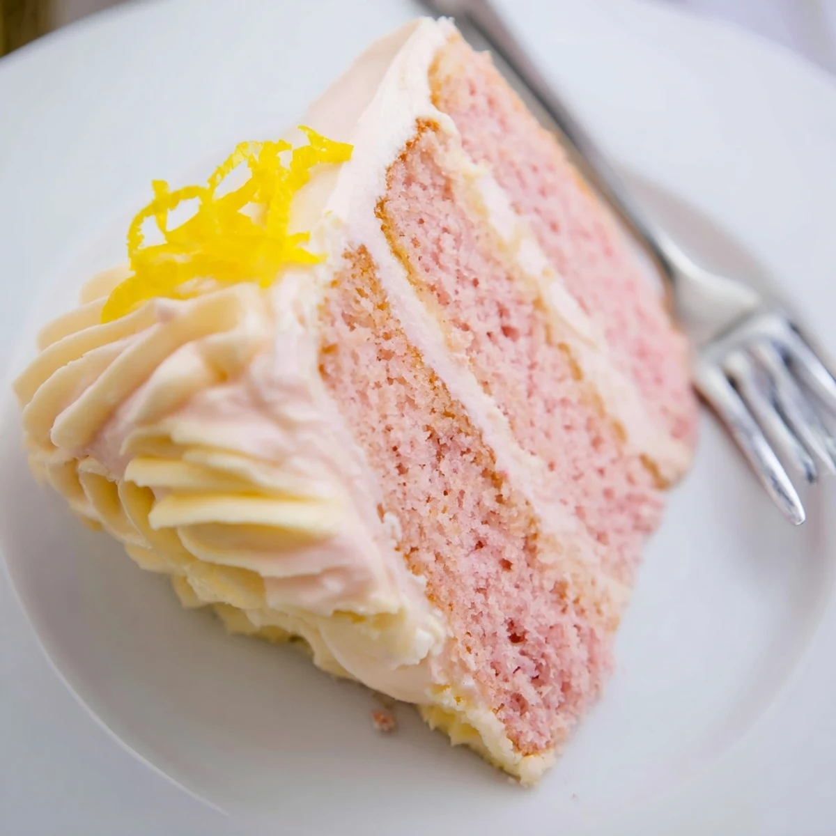 Close-up of Pink Lemonade Layer Cake showing moist, tender crumb and smooth, tangy frosting between layers.