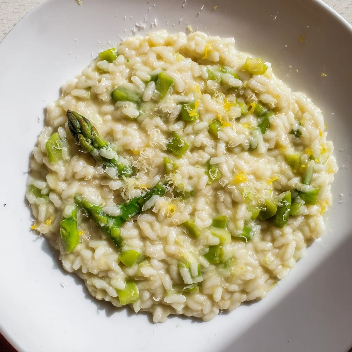 Steam rises from this vegetarian Date Night Risotto with Asparagus, showing a creamy texture and freshly grated Parmesan topping.