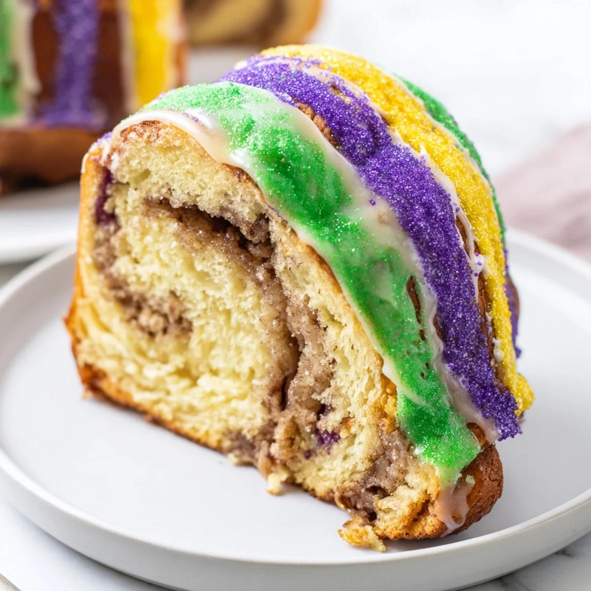 Glazed Mardi Gras King Cake with colorful sanding sugars on a rustic table, ready to serve with coffee.