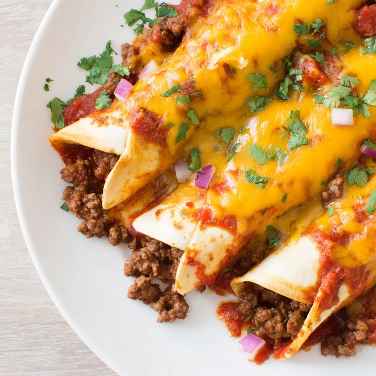 Close-up of Championship Beef Enchiladas with Red Sauce on a plate, served with a side of Mexican rice.