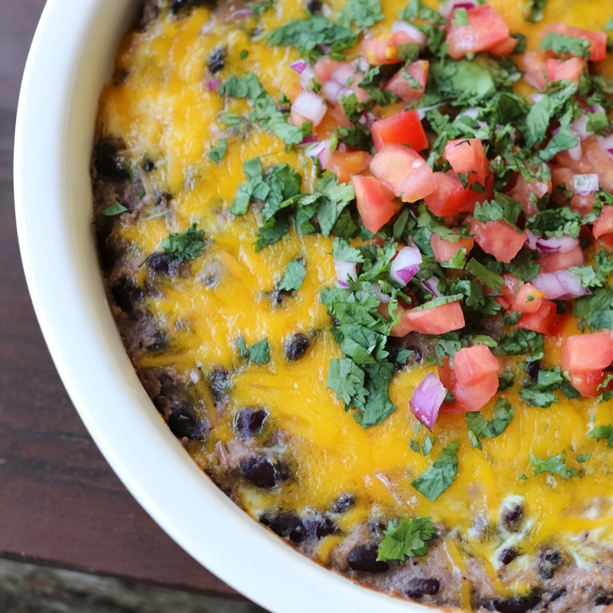 A close-up of cheesy Bean Dip with Cheddar Cheese, topped with chopped cilantro, served with crisp pita chips for dipping.