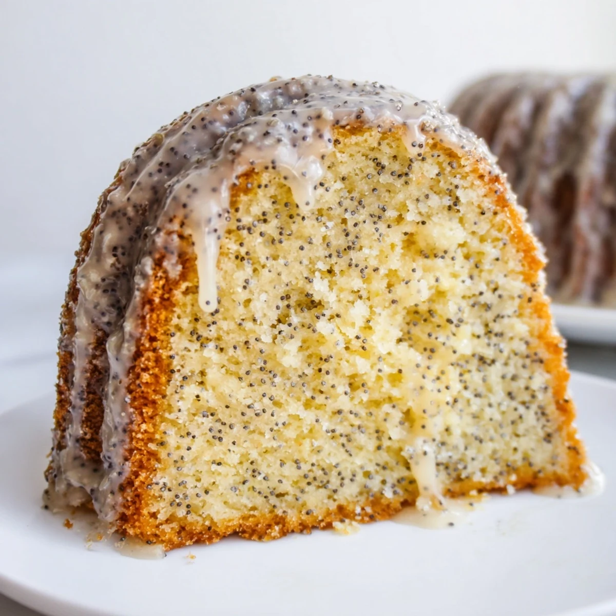 Homemade Lemon Poppy Seed Bundt Cake sliced to reveal fluffy interior, garnished with fresh lemon zest and a teacup.