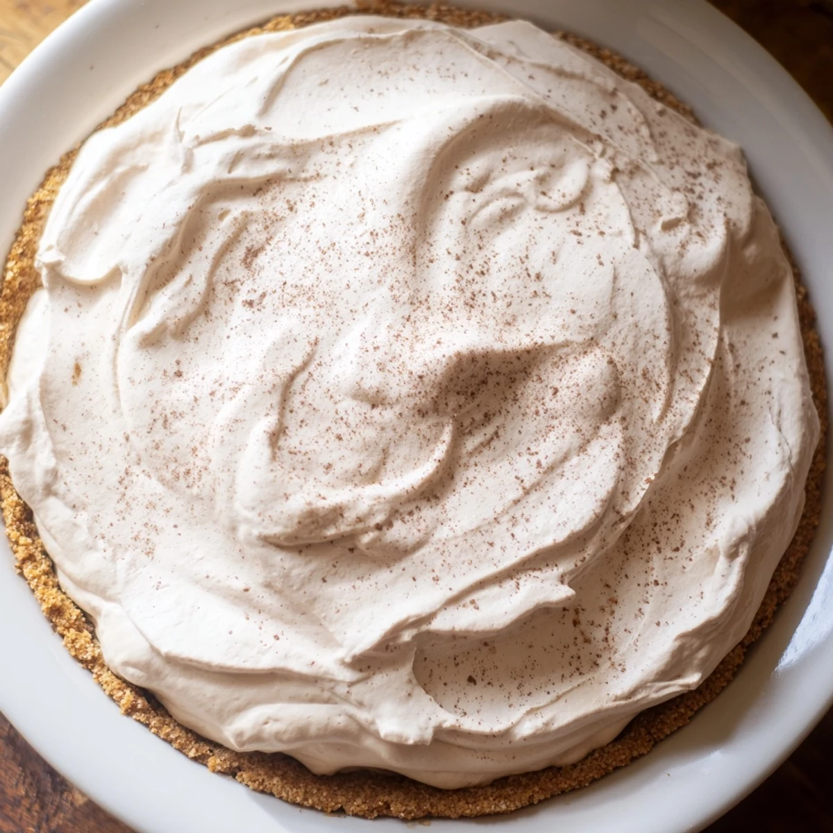 Creamy keto cold brew coffee pie with whipped topping on an almond flour crust, garnished with coffee beans.  