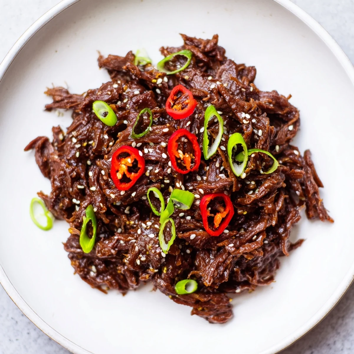 Tender shredded beef with savory-sweet sauce in crisp lettuce cups, garnished with chili.  