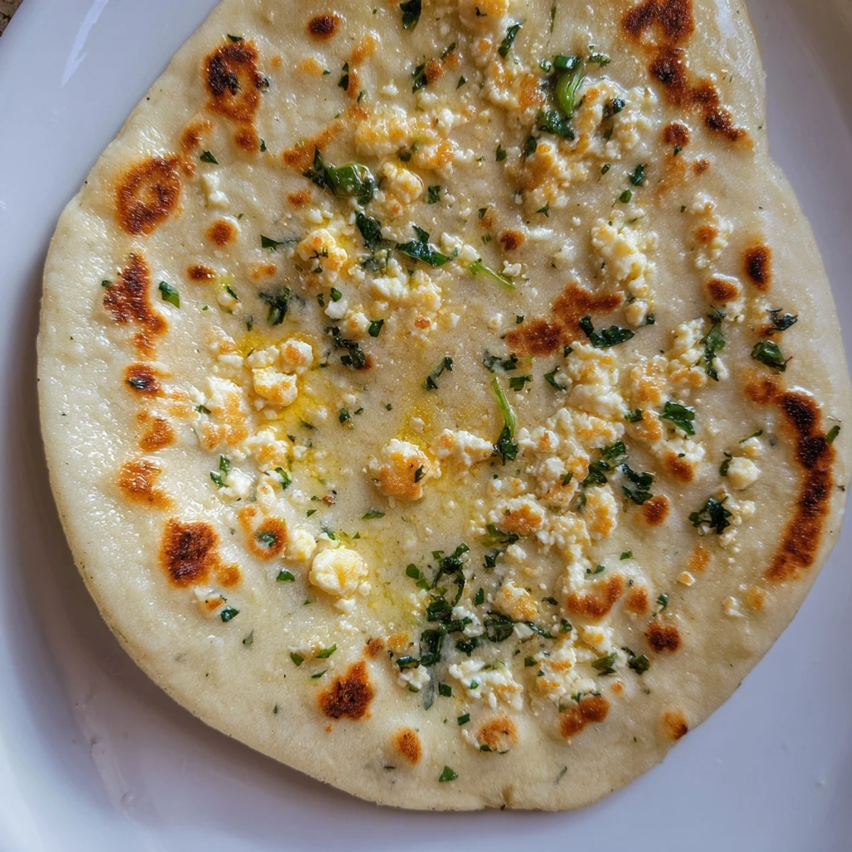 Soft, pillowy Cottage Cheese Garlic Naan brushed with garlic butter, resting on a wooden board next to a bowl of dal.