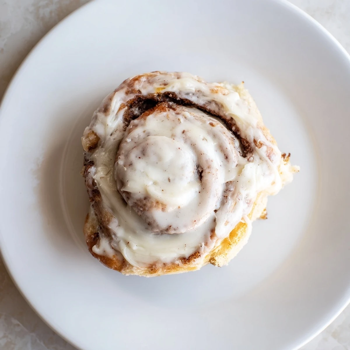 Freshly baked Keto Cinnamon Buns with a gooey cinnamon filling and creamy icing on a wooden board.