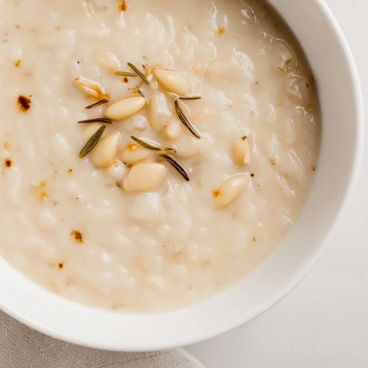 A warm bowl of Rosemary and Roasted Garlic White Bean Soup garnished with fresh parsley and a drizzle of olive oil.