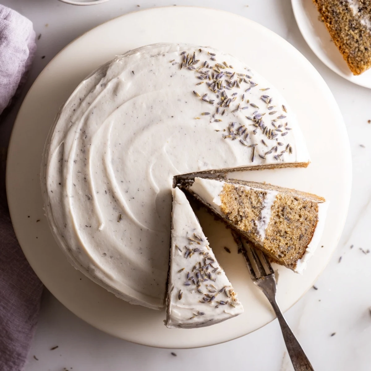 London Fog Cake with Earl Grey and Lavender is frosted, layered, and garnished with dried lavender on a rustic wood table.