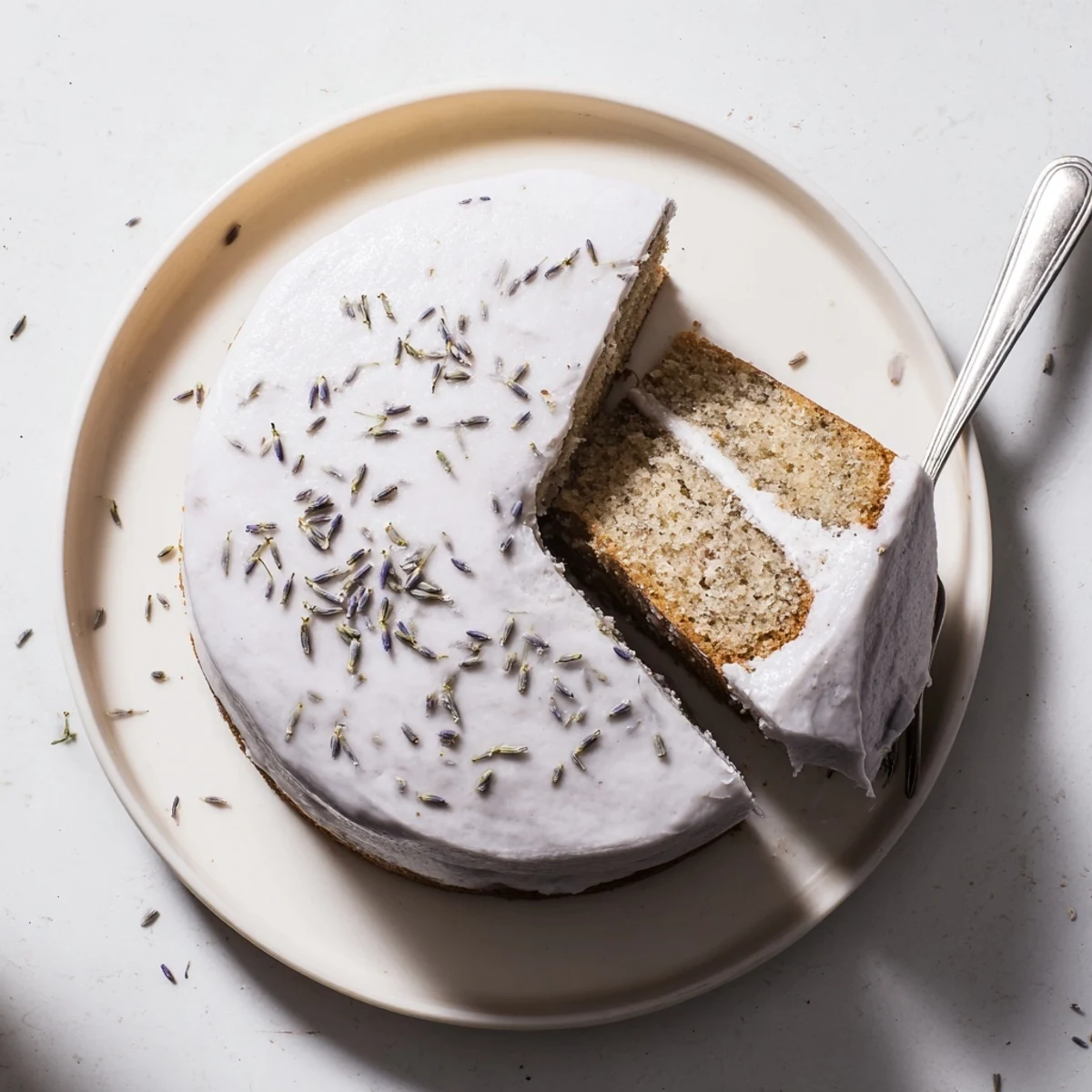 A close-up of London Fog Cake with Earl Grey and Lavender reveals tender crumb, smooth frosting, and floral lavender garnish.