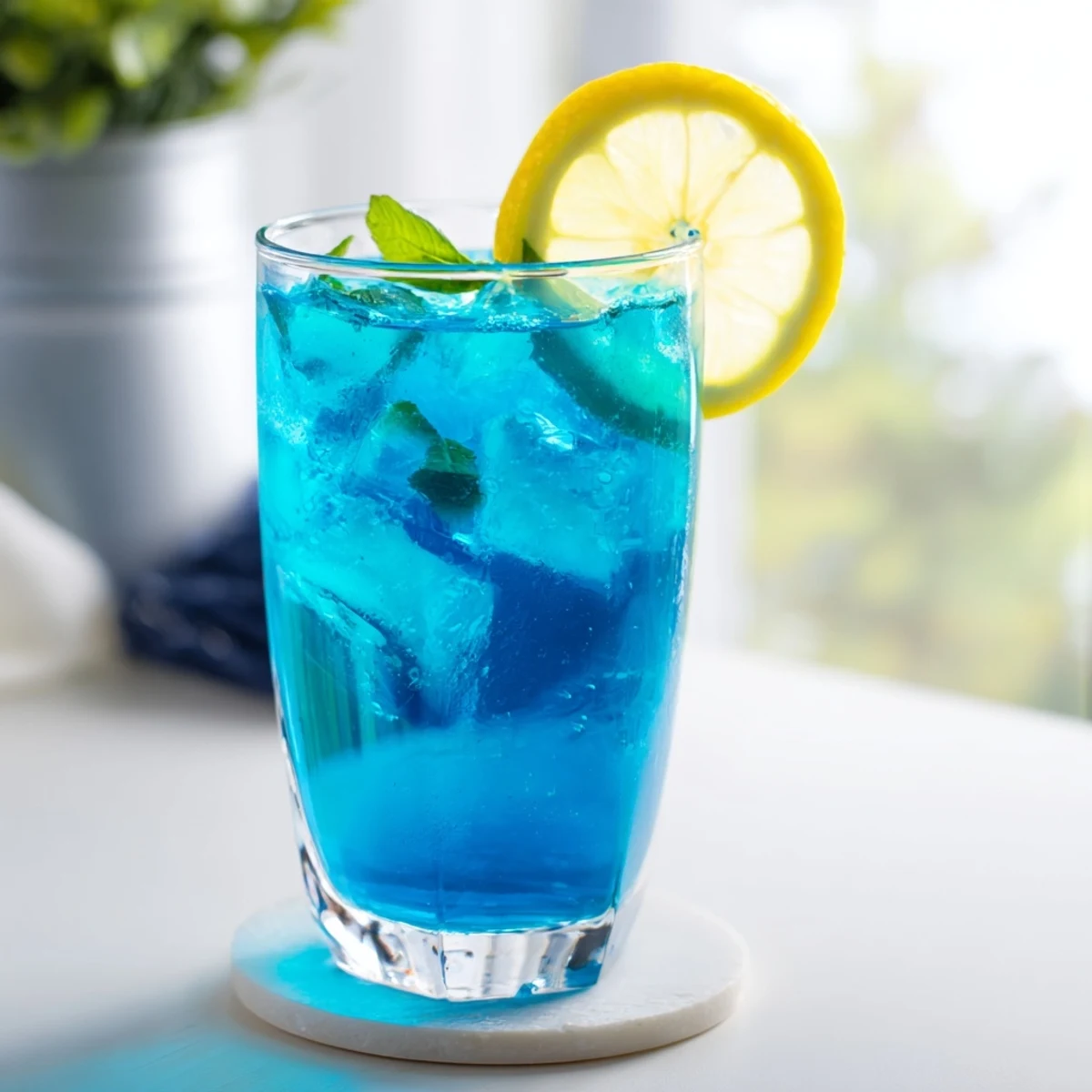 A tall glass of Blue Spirulina Lemonade, bright blue and garnished with lemon slices.