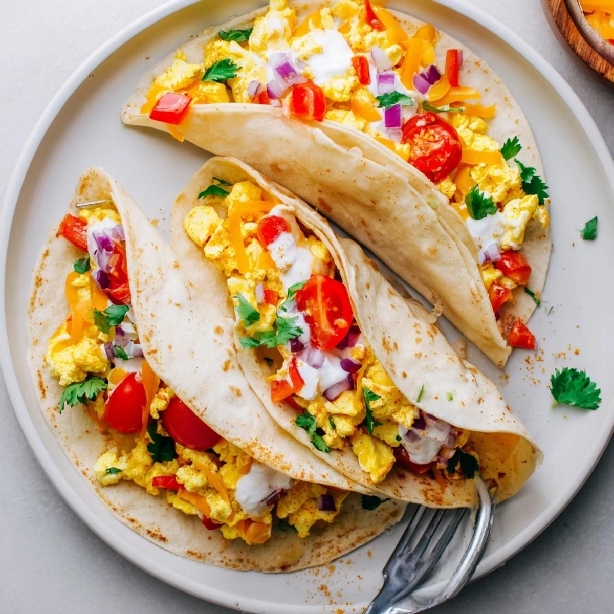 Hands holding a warm Tex Mex Egg Tortilla Pockets filled with sautéed veggies, melted cheddar, and a dollop of sour cream.