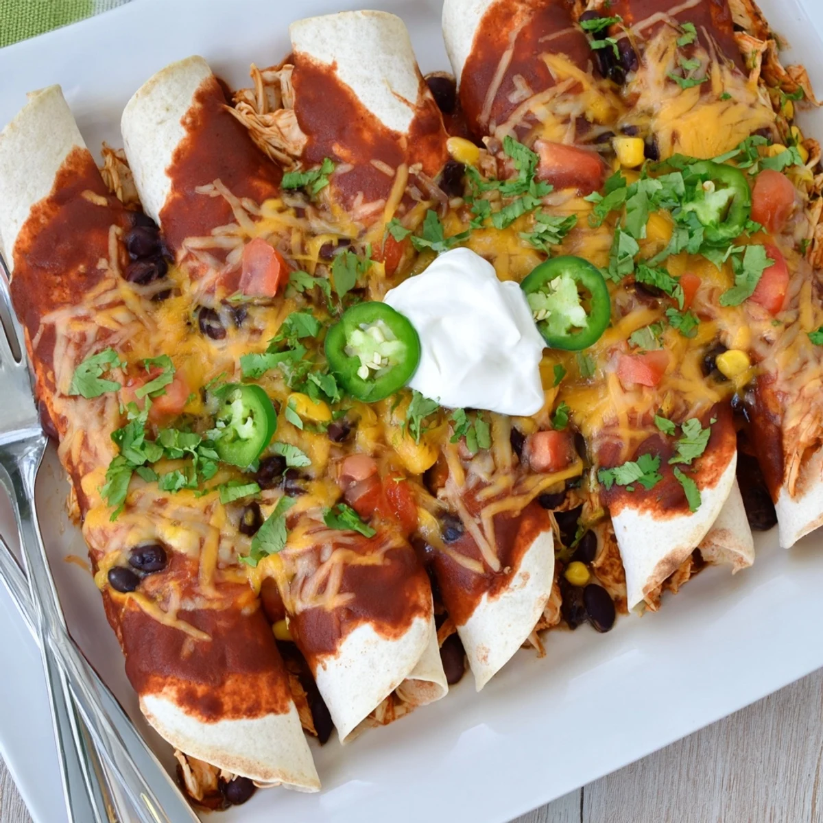Cheesy baked Chicken Enchiladas filled with tender shredded chicken in a zesty red sauce.  