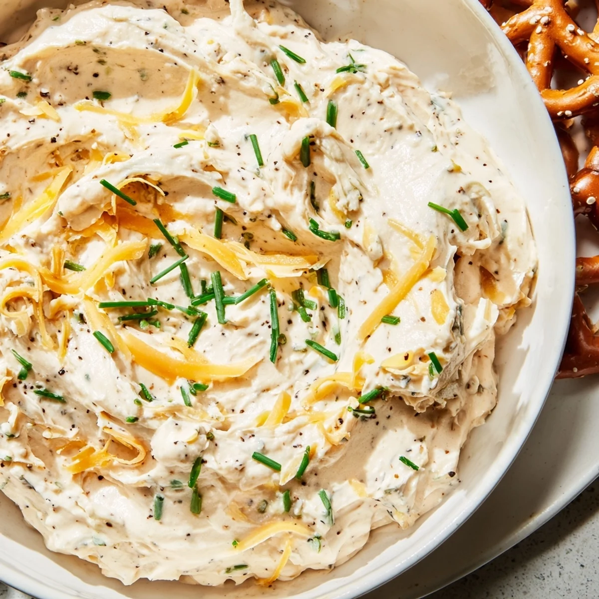 Golden cheese-infused savory pretzel dip topped with green onions, perfect for dipping warm pretzel twists at parties