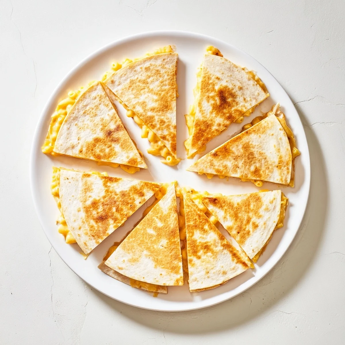 Golden crispy mac and cheese quesadillas sliced into wedges on a white plate