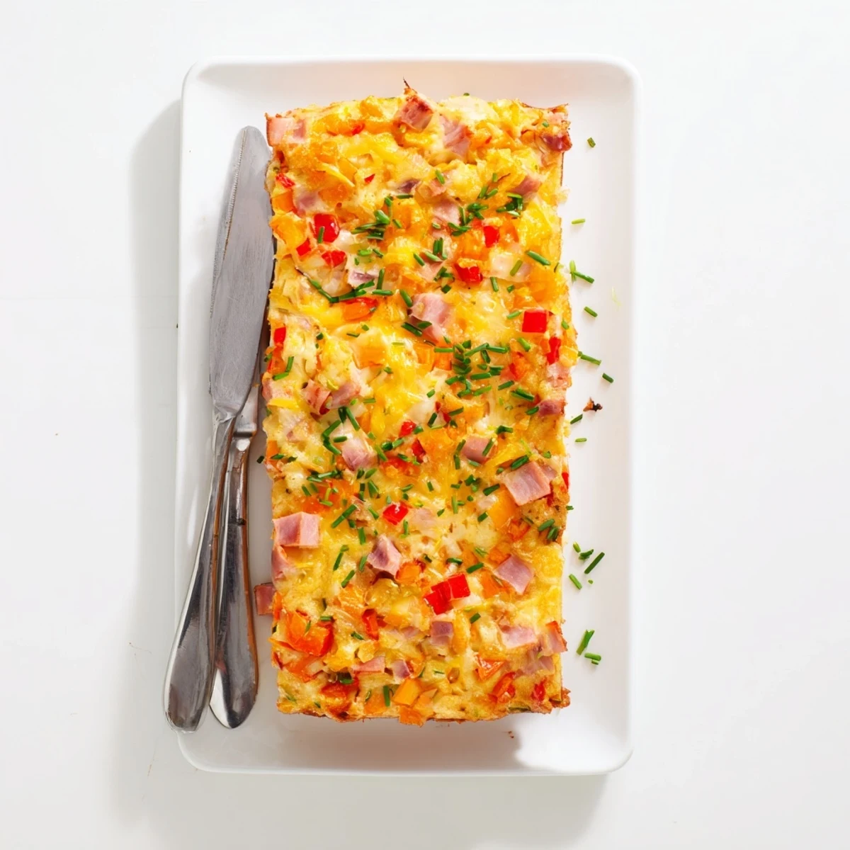 Savory vegetable and ham slice on a white serving plate with fresh herb garnish