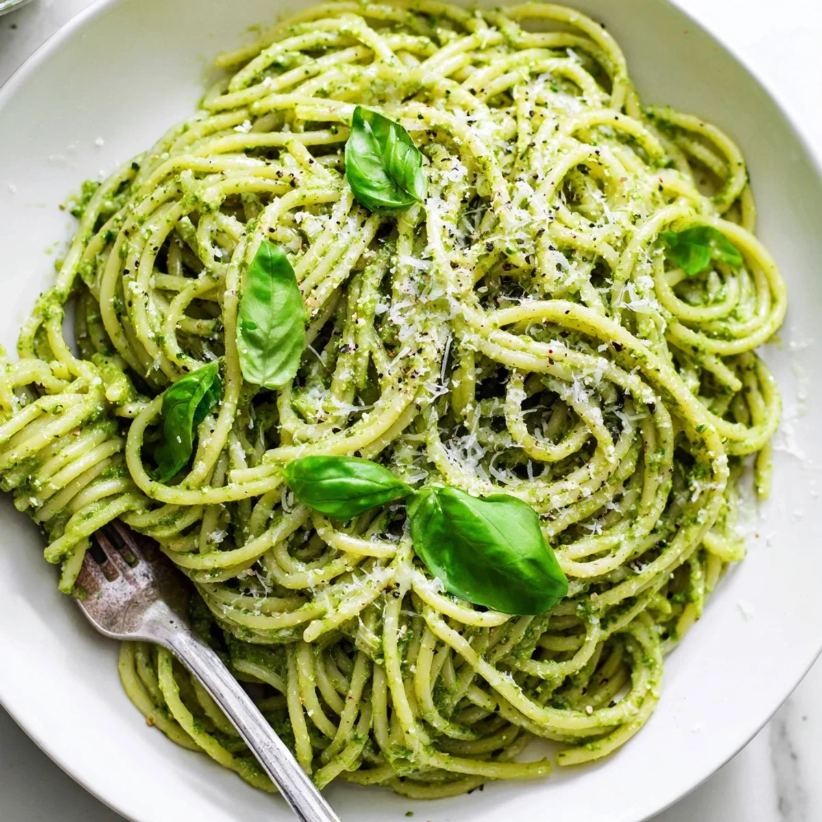 Vibrant green pesto pasta featuring ripe avocado blended with fresh spinach and basil over al dente spaghetti