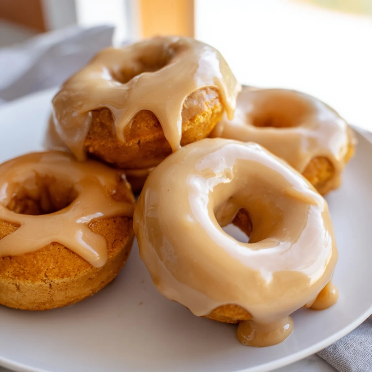 Pumpkin mochi donuts topped with glossy maple glaze on a wire rack ready for fall breakfast treats