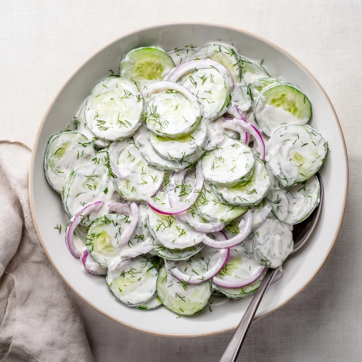 Creamy cucumber salad with crisp sliced cucumbers and red onions in a tangy white dressing