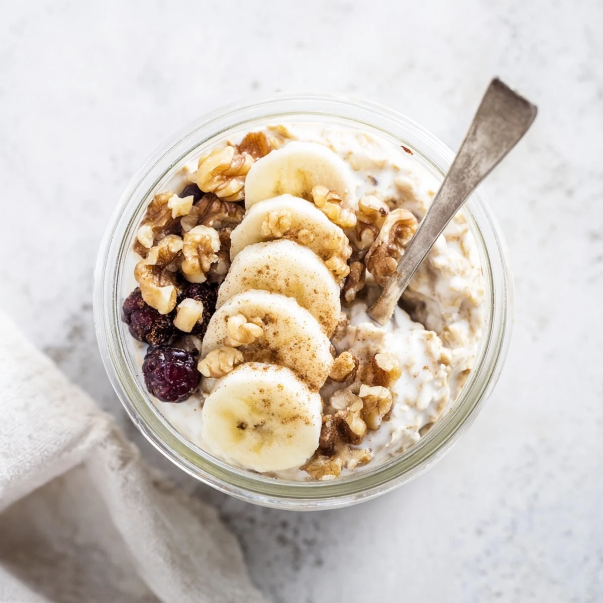 Creamy brown sugar overnight oats topped with fresh banana slices and crunchy walnuts in a glass jar.