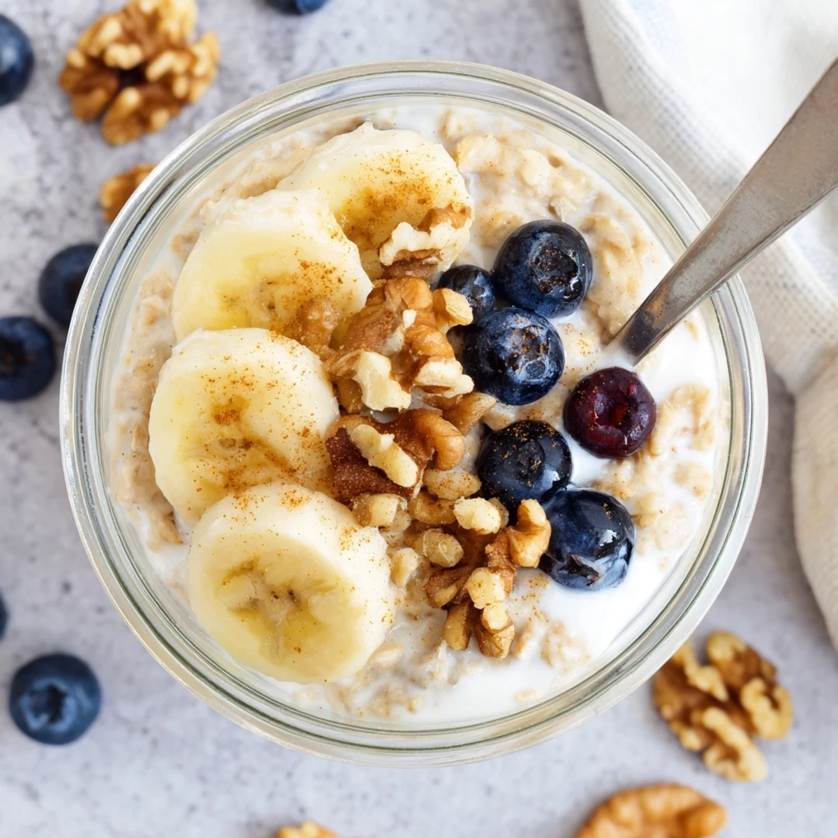 Golden brown sugar overnight oats layered with Greek yogurt, cinnamon, and colorful berries for breakfast.