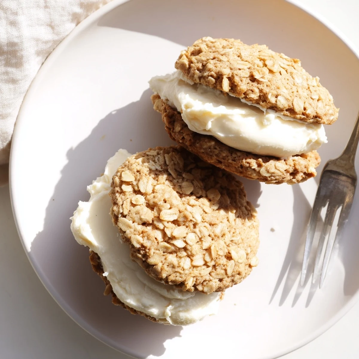 Two soft oatmeal cookies stacked with thick white vanilla cream filling creating these classic homemade oatmeal cream pies