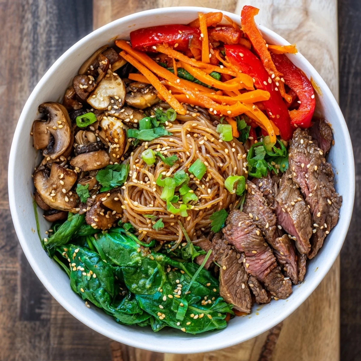 Steaming bowl of Korean beef noodles with tender meat slices, colorful vegetables, and chewy noodles coated in savory-sweet gochujang sauce