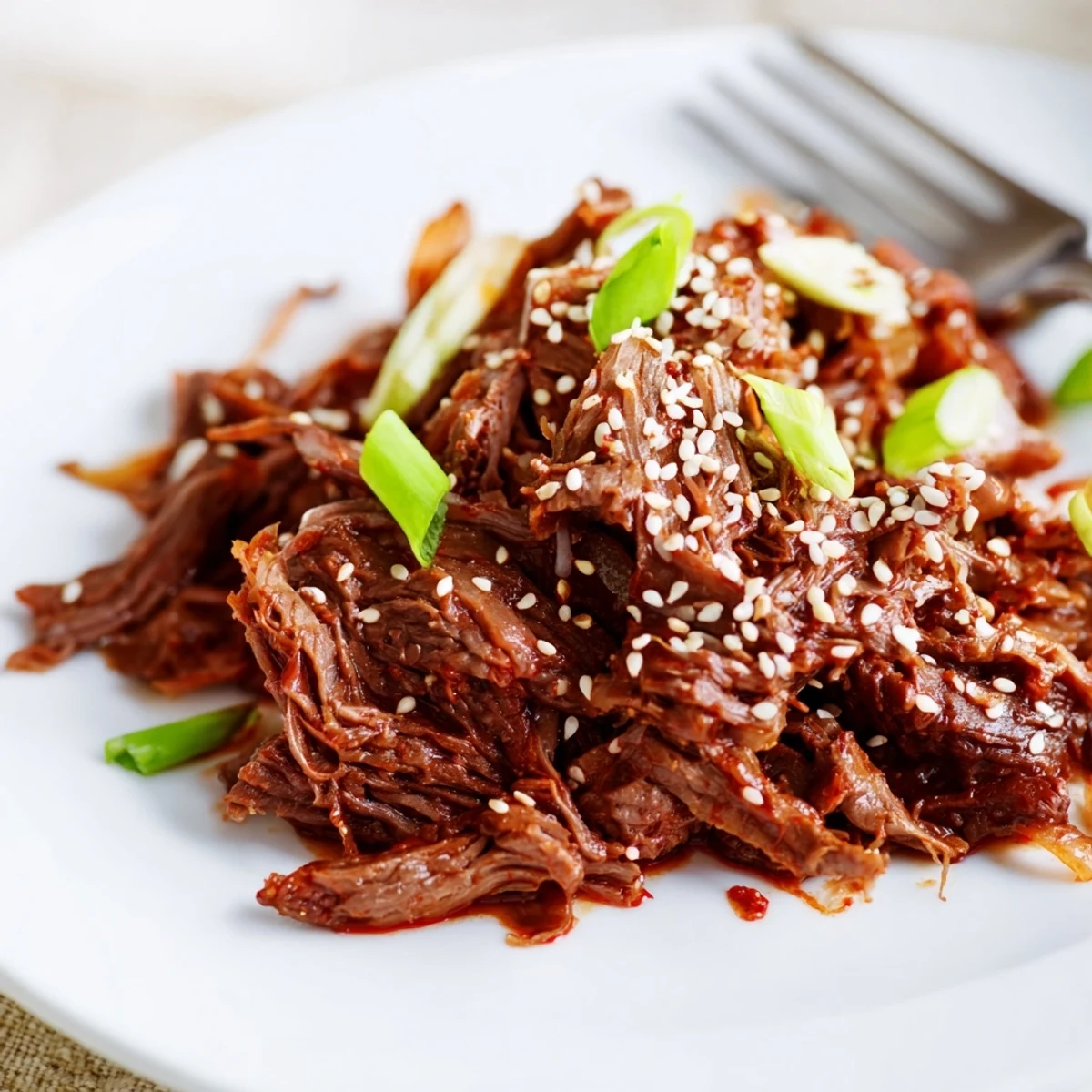 Tender slow cooker Korean beef shredded in a rich savory-sweet sauce with sesame seeds