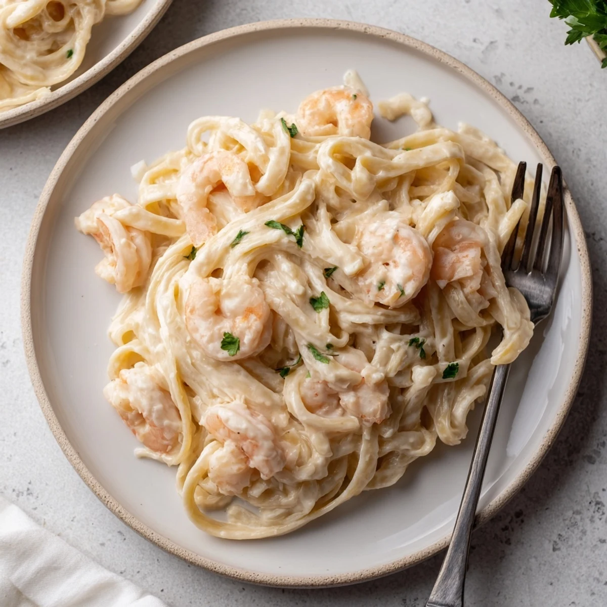 Garnished one pan shrimp fettuccine Alfredo featuring al dente pasta swimming in white cheese sauce with parsley