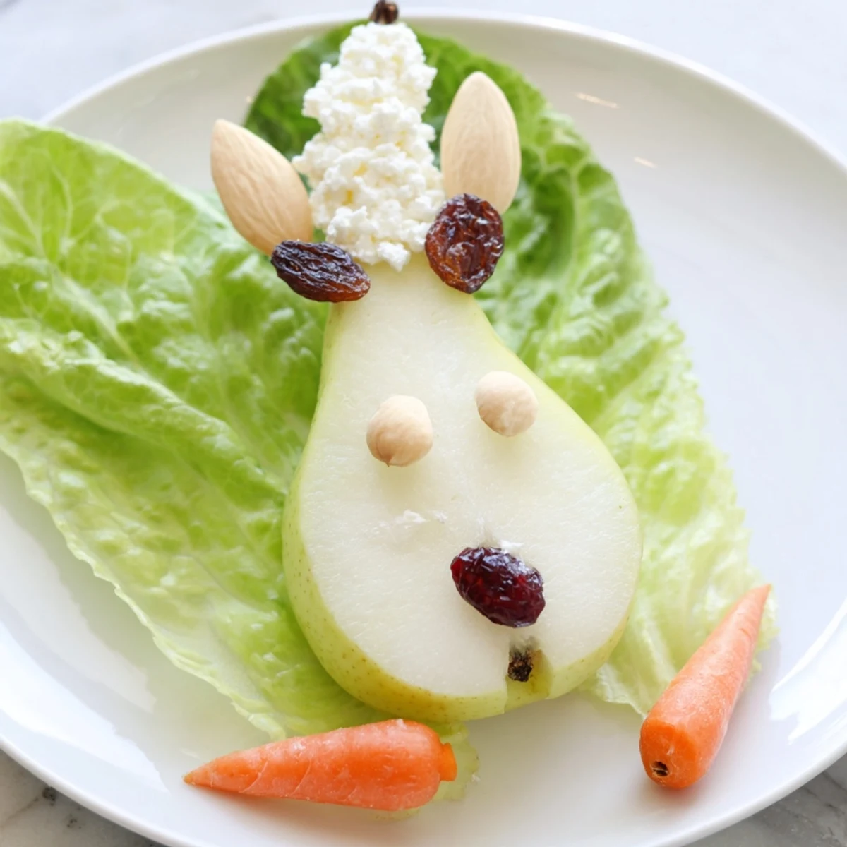 Pear bunny salad featuring cute pear halves with almond ears and raisin eyes on lettuce leaves