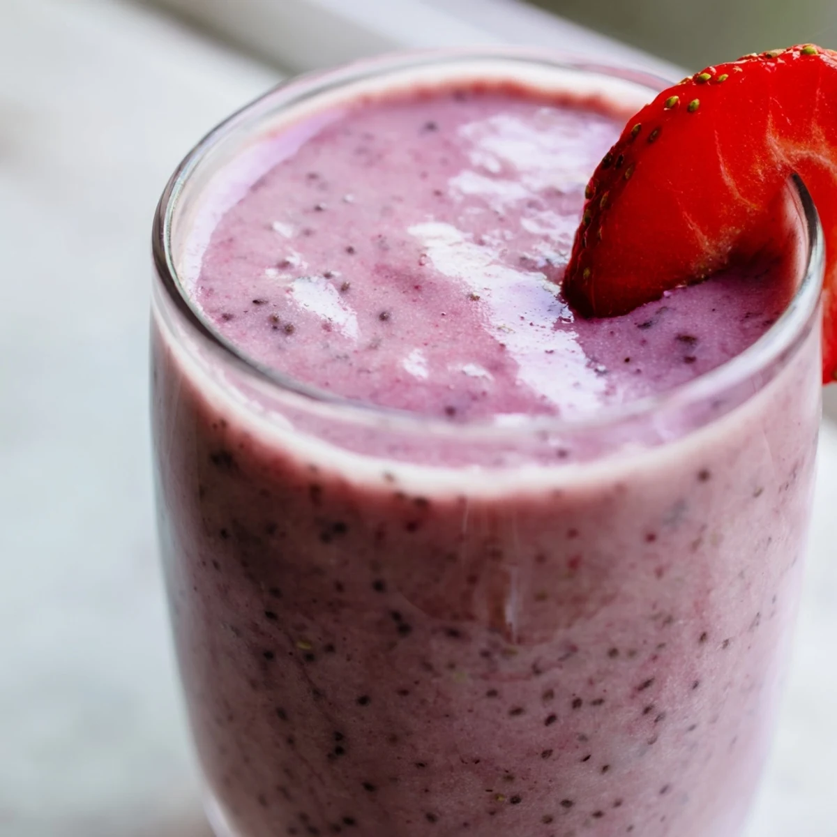 Vibrant pink blended drink featuring fresh strawberries Greek yogurt banana and optional chia seeds for protein