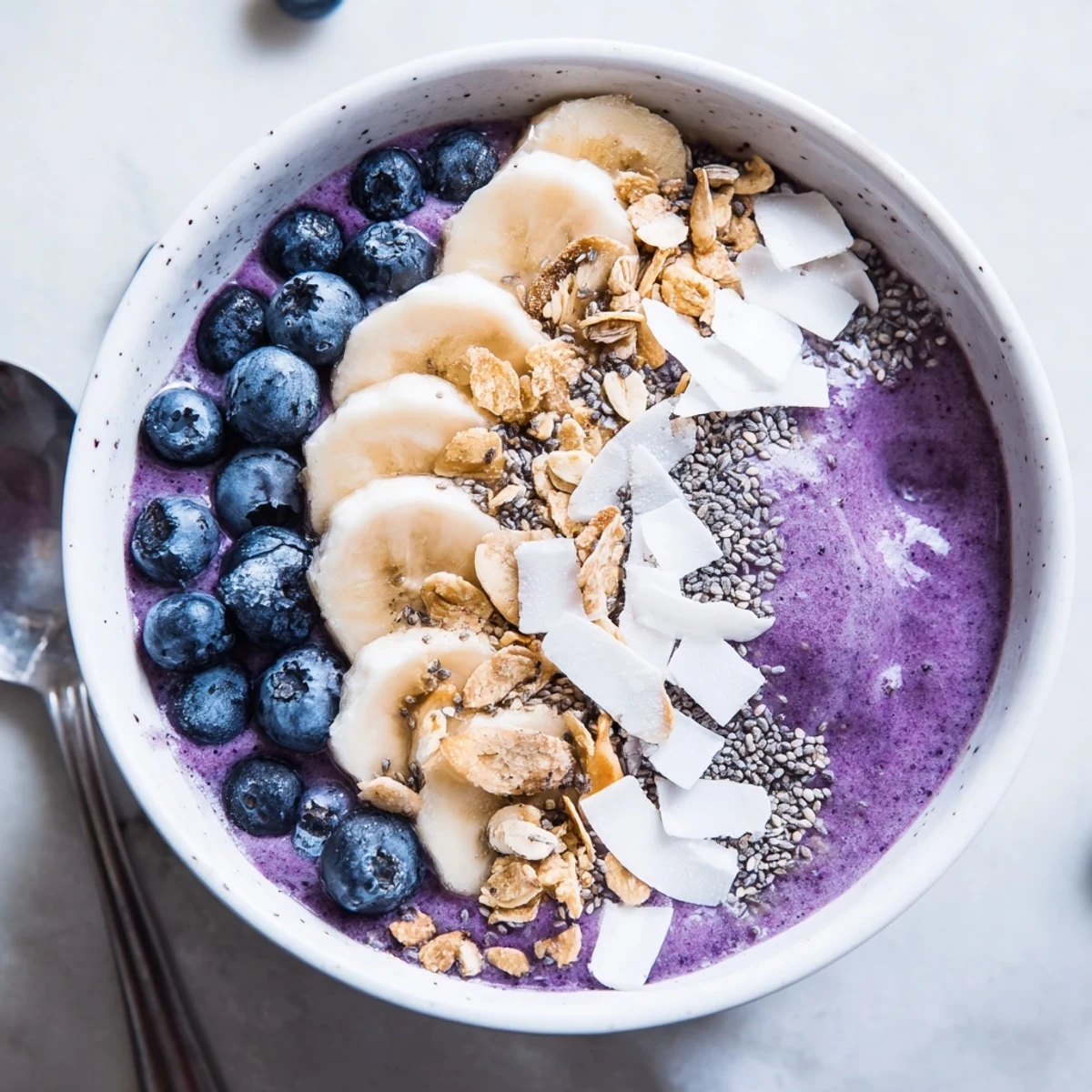 Creamy blueberry smoothie bowl with Greek yogurt topped with fresh berries, granola, and coconut flakes