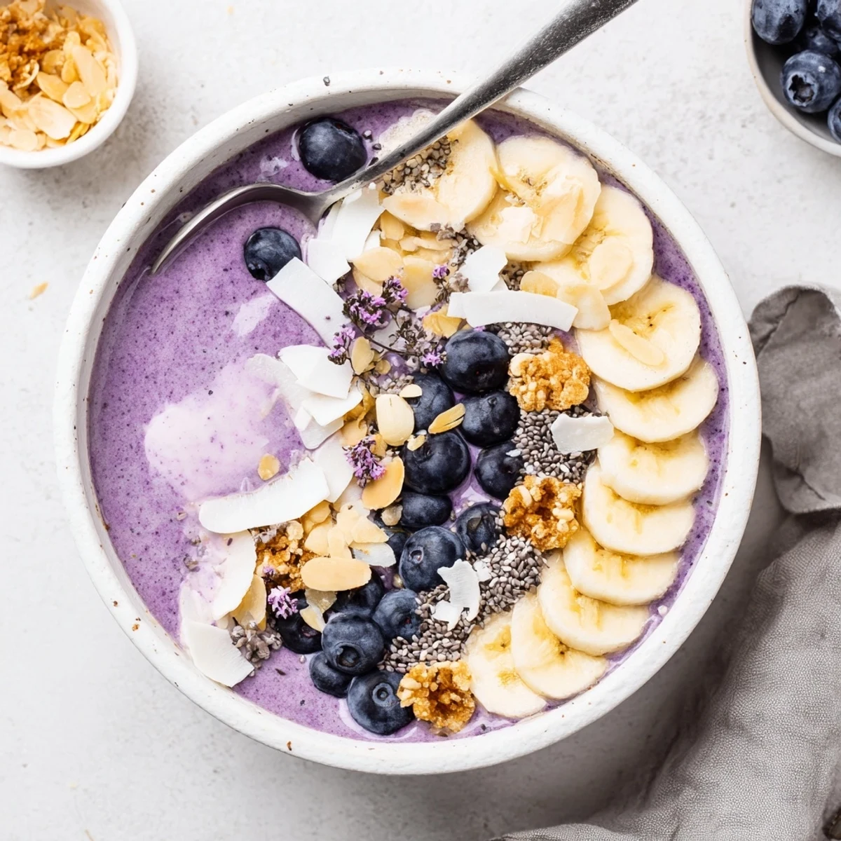 Thick purple smoothie bowl made from blended blueberries and Greek yogurt with banana slices and chia seeds