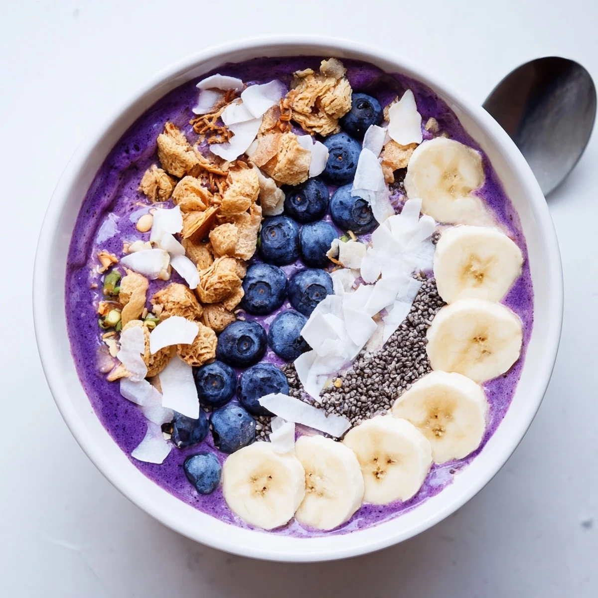 Vibrant breakfast smoothie bowl featuring Greek yogurt blueberry base layered with granola and sliced almonds