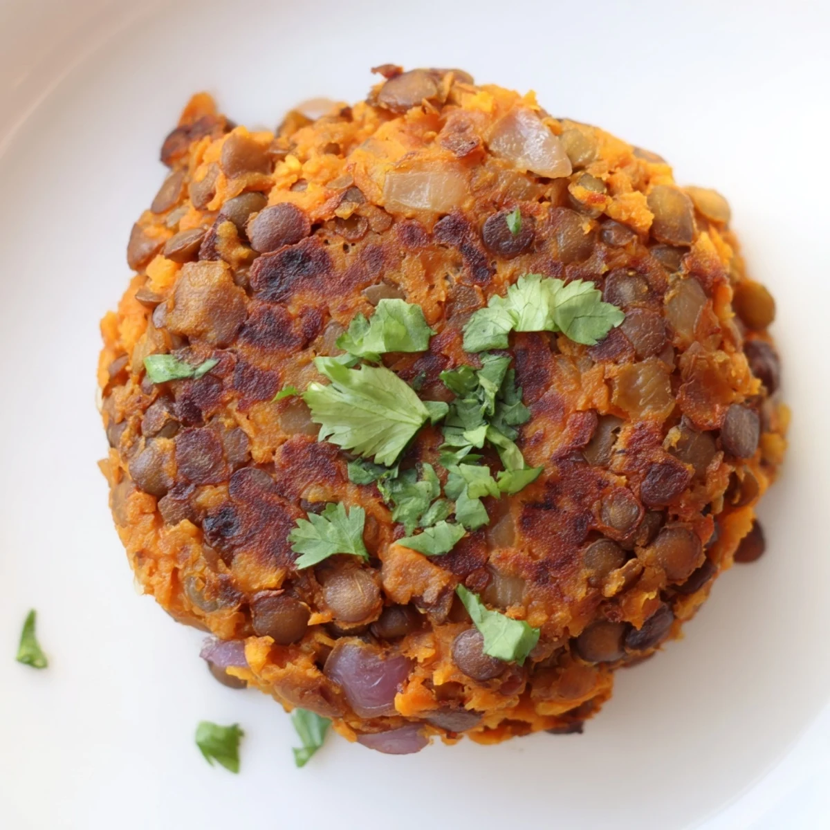 Crispy pan-fried sweet potato patties with lentils garnished with green cilantro leaves