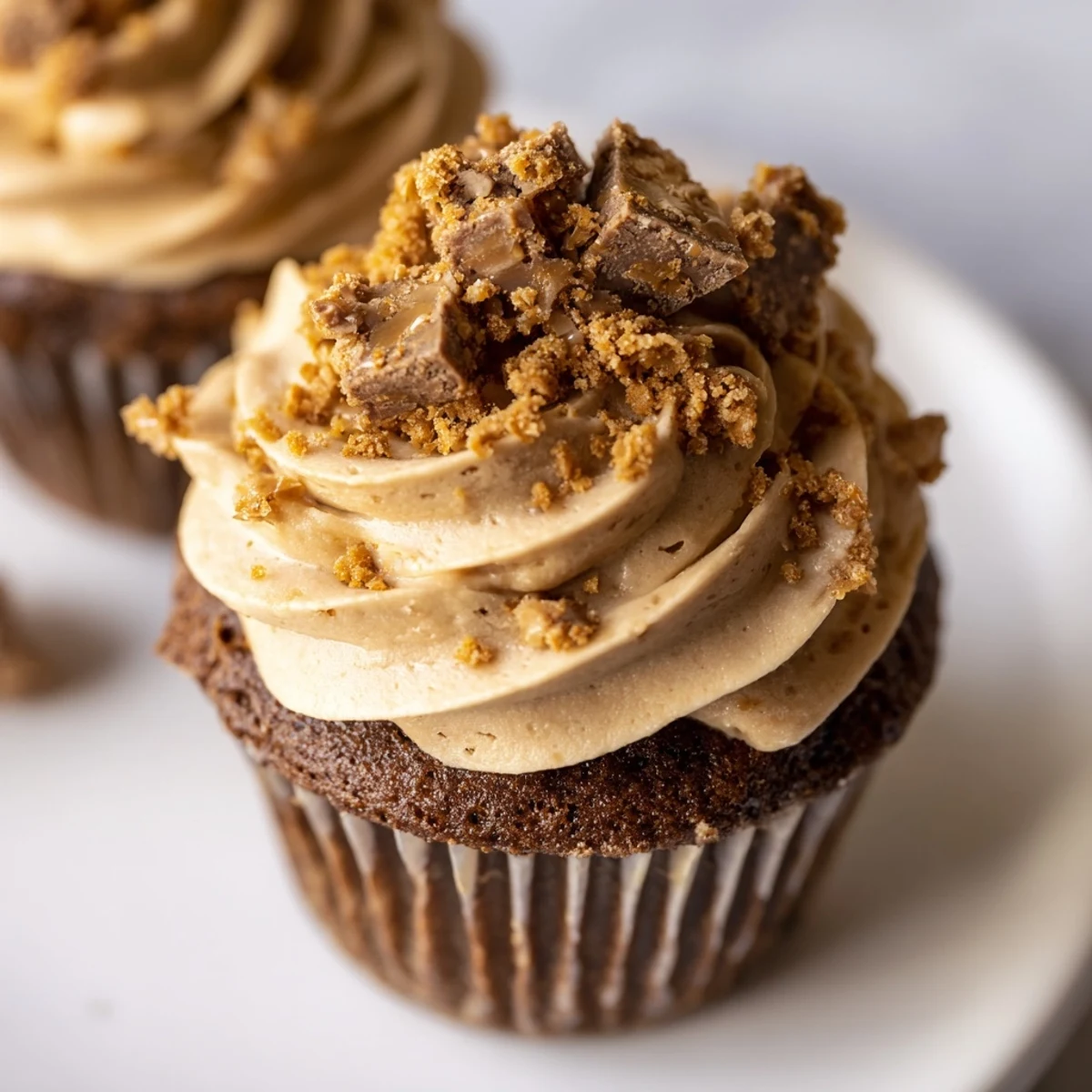Decadent Butterfinger cupcakes topped with creamy peanut butter frosting and crunchy candy bar pieces