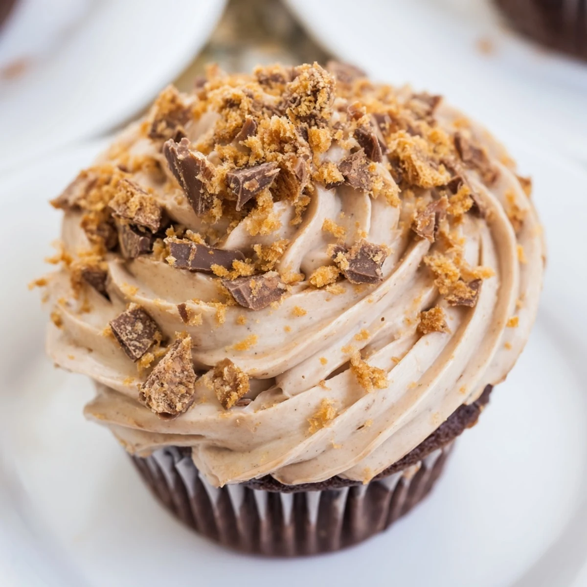 Chocolate cupcakes with peanut butter center, Butterfinger frosting, and candy bar garnish on plate