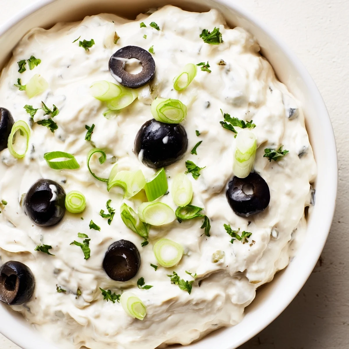 Tangy cream cheese olive spread topped with chopped black and green olives on a serving platter