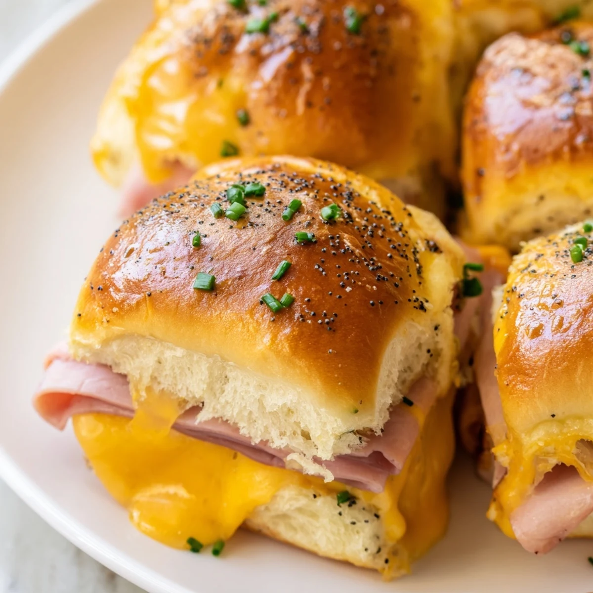 Bite-sized Hawaiian roll grilled cheese appetizers with gooey cheese and poppy seed topping