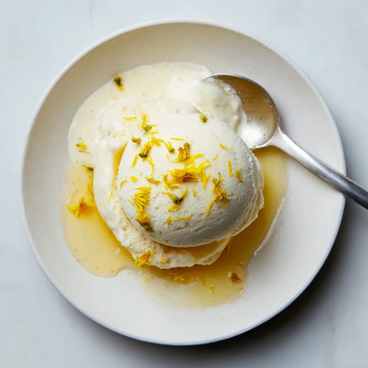 Golden scoop of dandelion honey ice cream topped with fresh yellow petals