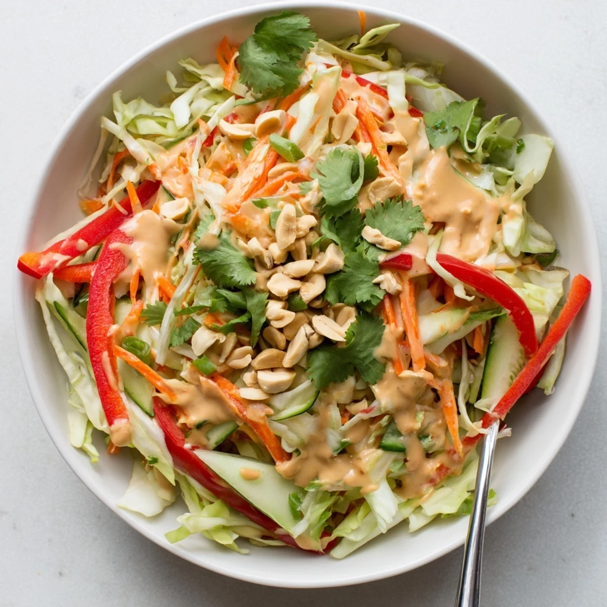 Simple Thai salad peanut sauce tossed with crunchy carrots cucumbers and roasted peanuts