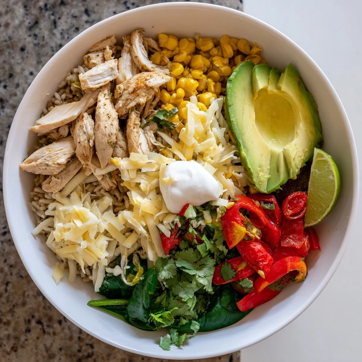 Flavorful Southwest spice green chile bowl featuring spiced chicken over brown rice with melted Monterey Jack and cilantro