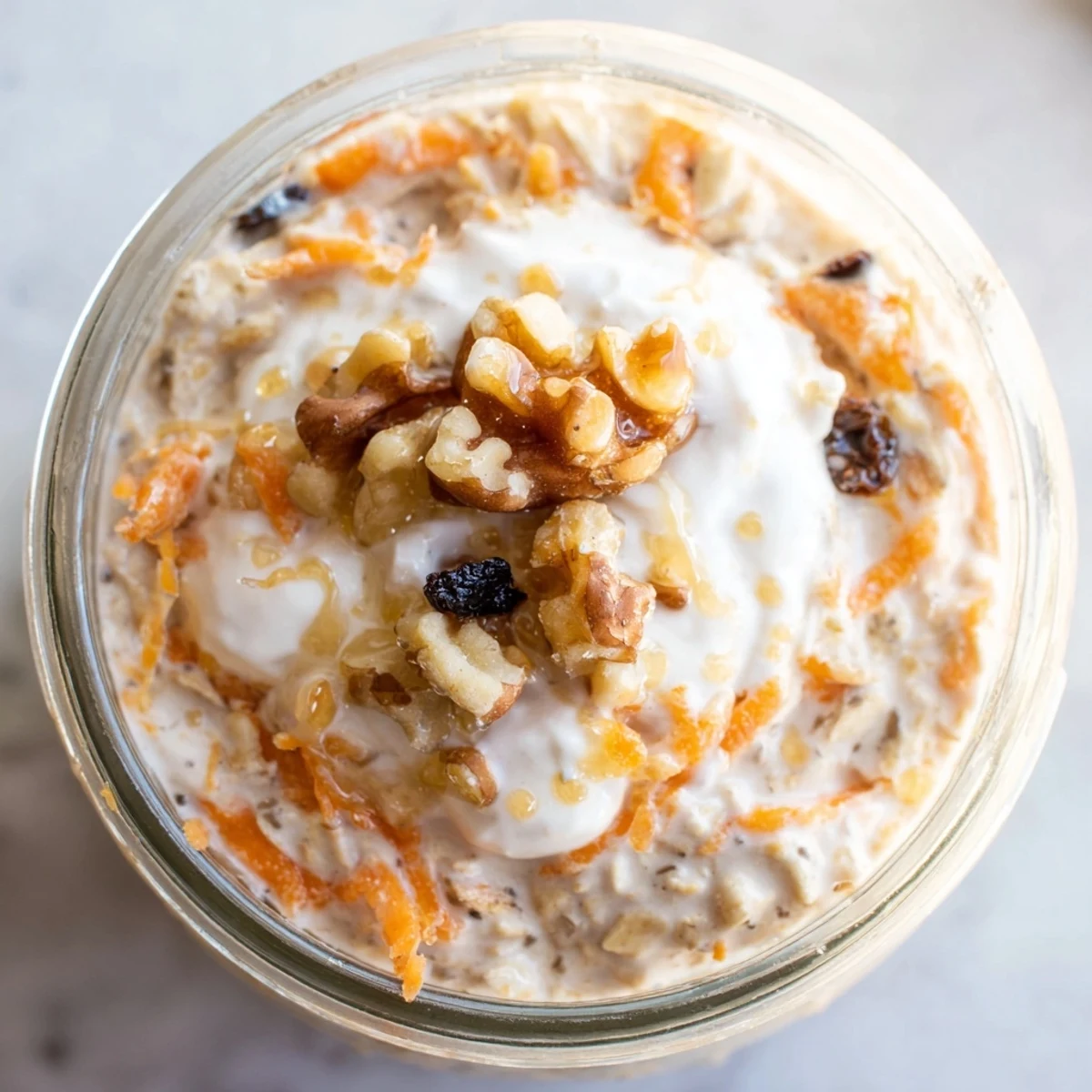 Creamy carrot cake overnight oats topped with walnuts and raisins in a glass jar