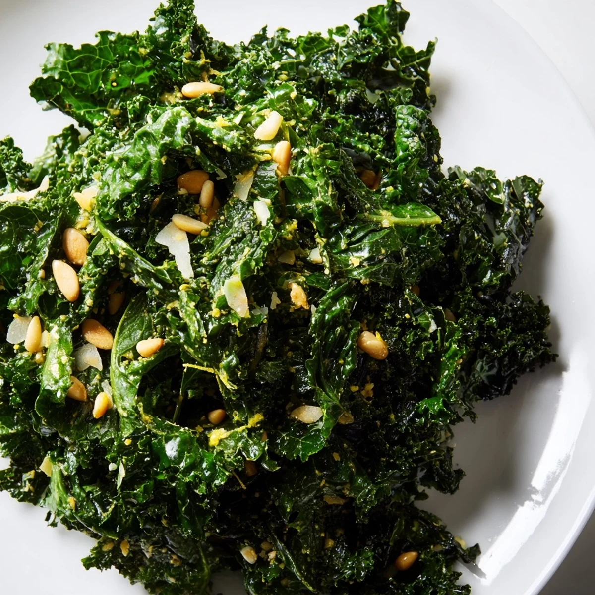 Garlic Lemon Parmesan Kale Salad in a rustic wooden bowl with shaved cheese and toasted pine nuts