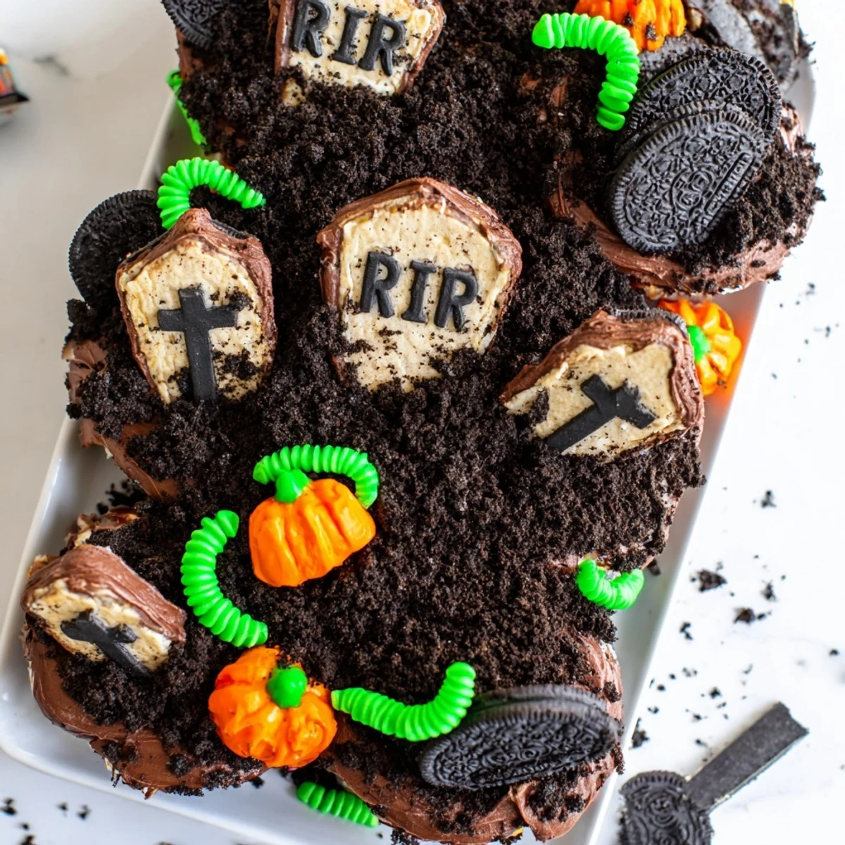 Pull Apart Graveyard Cupcakes topped with chocolate frosting and crumbling cookie dirt on a festive Halloween platter