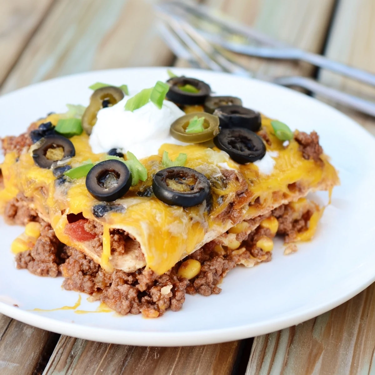 Cheesy Nacho Casserole bubbling golden with melted cheddar, tortilla chips peeking